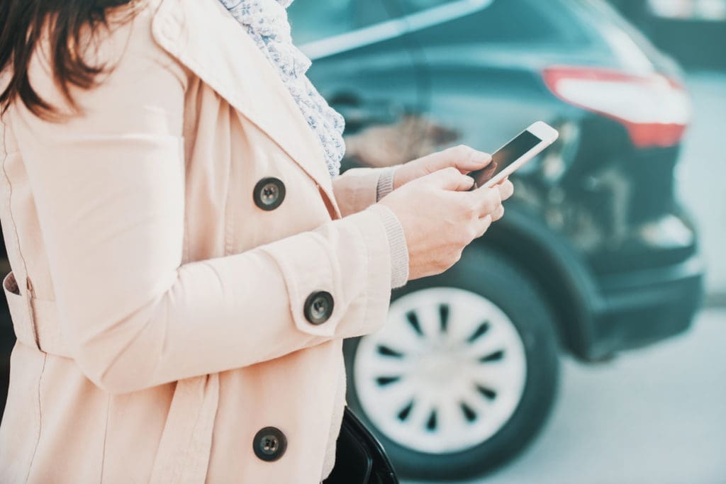 Woman texts on her smartphone in a parking lot