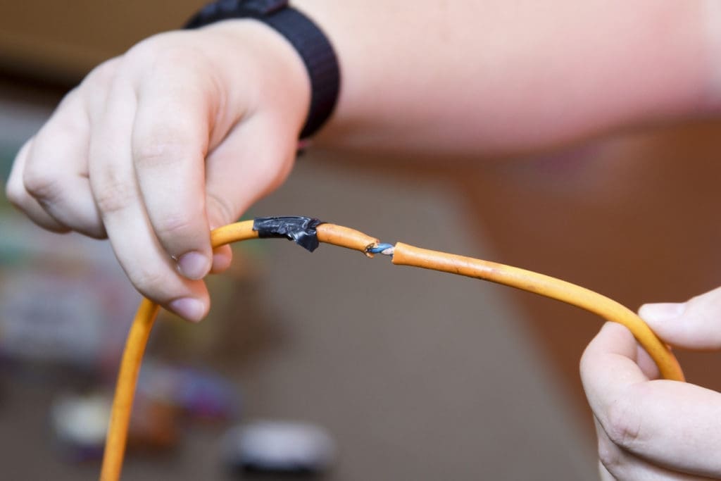 A person holds up an orange wire and demonstrates workplace electrical safety