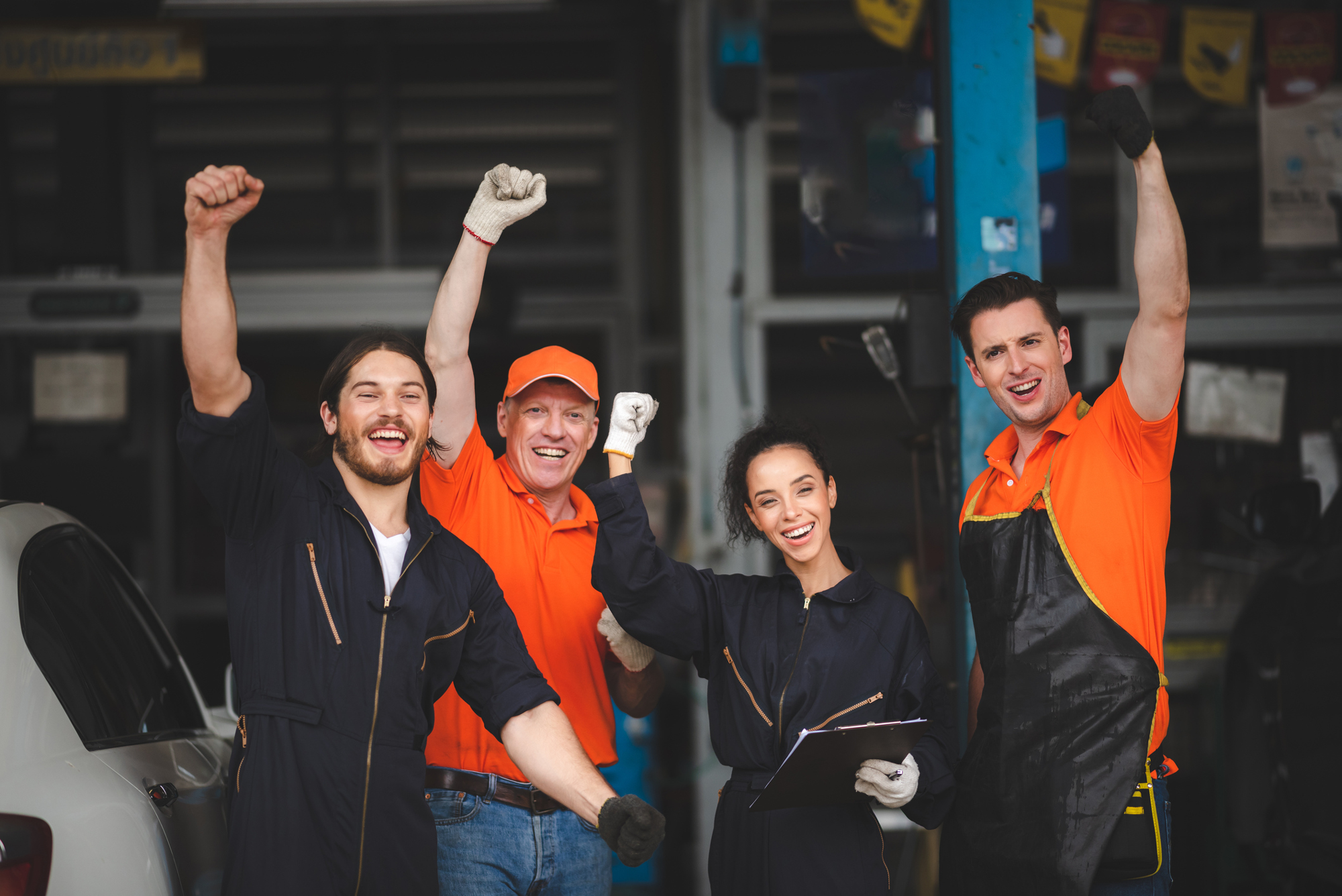 Auto repair shop workers pump their fists in the air together
