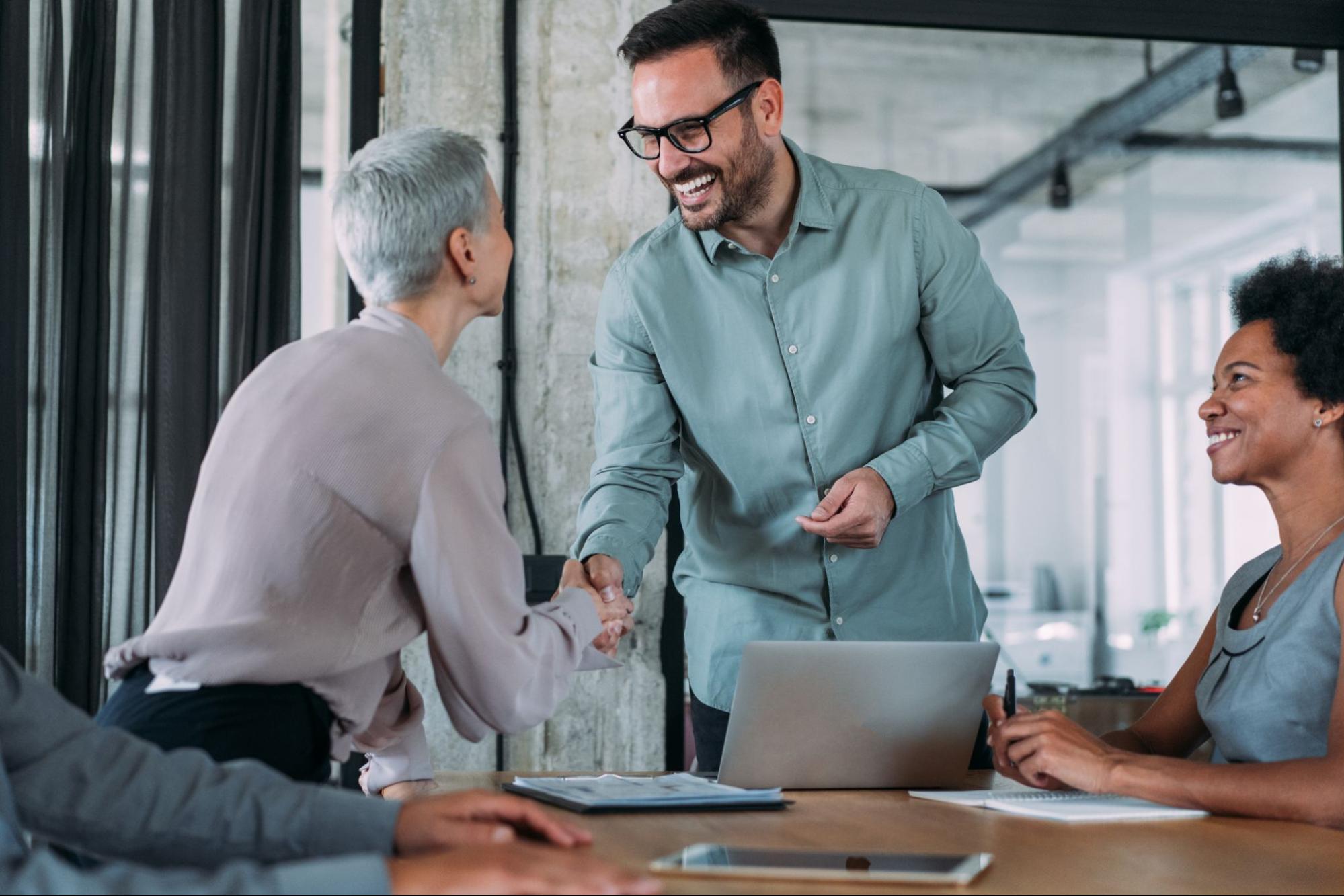 Business people smile and shake hands at the end of a successful meeting.