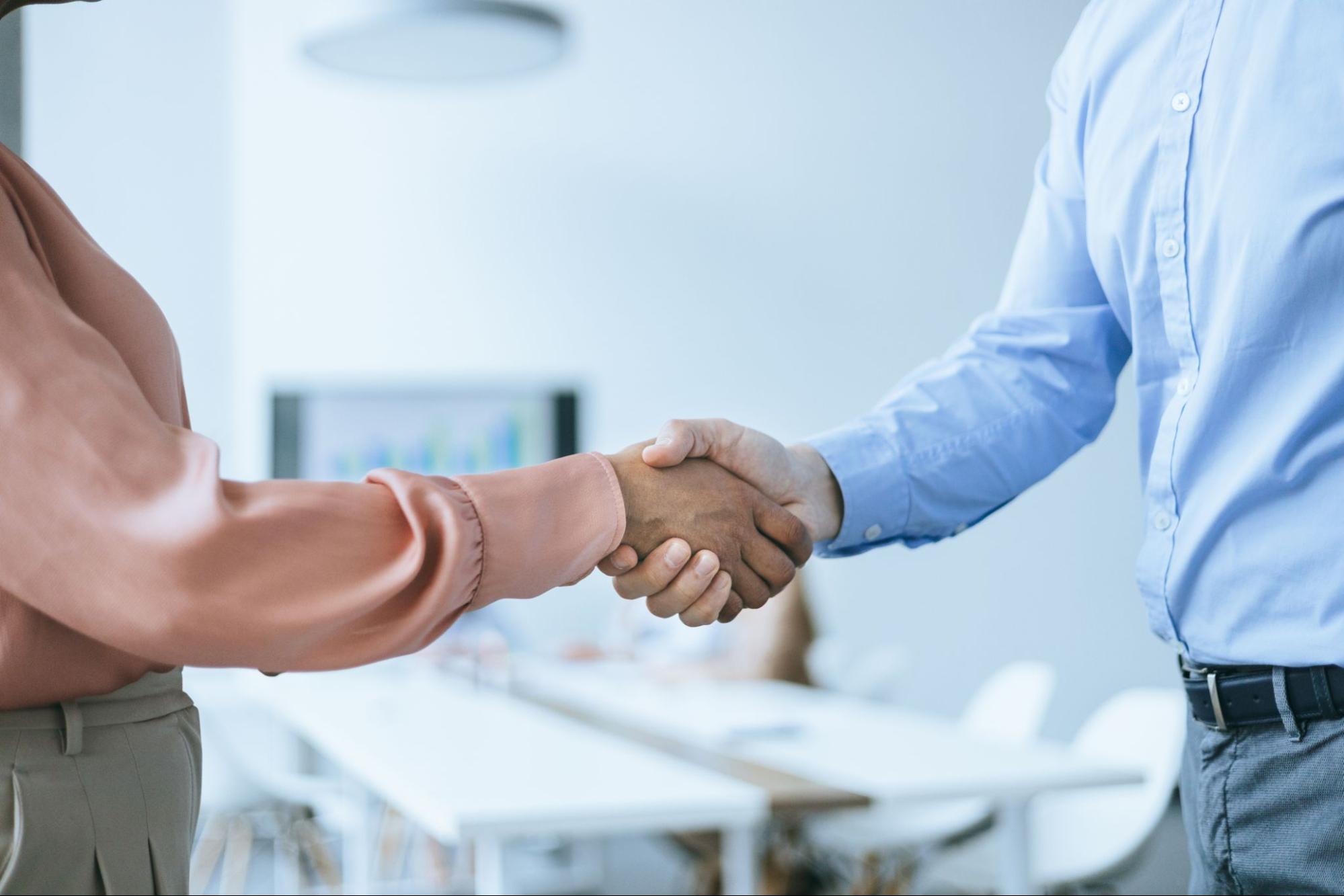 Two people in business attire shake hands.